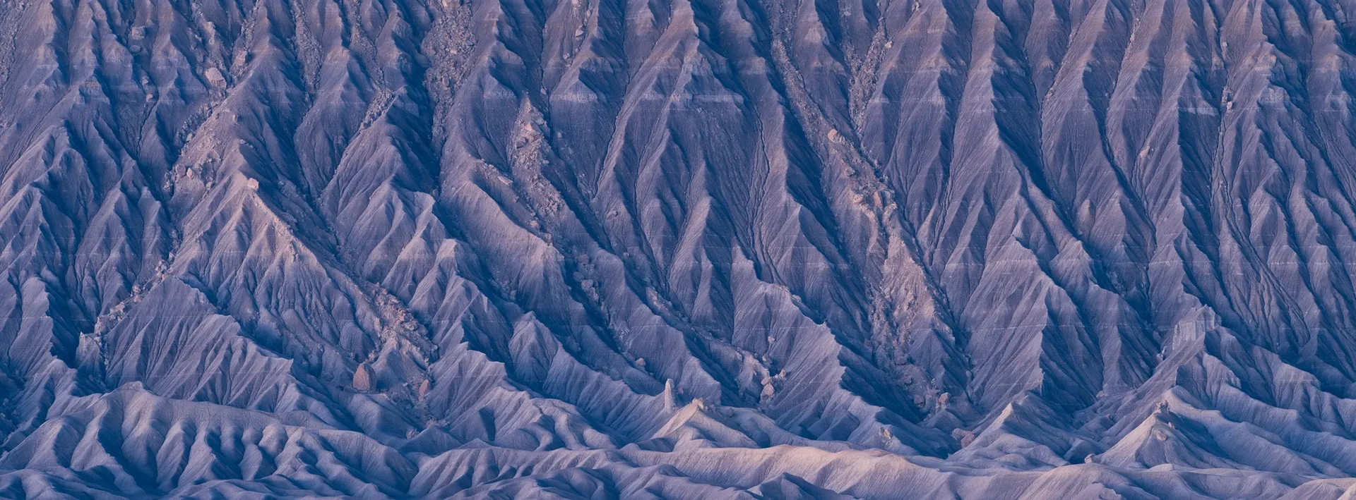 Factory Butte before sunrise in the Utah badlands, the mesa's silhouette rising from flat terrain as predawn light begins to define the sky. Photograph by Marty Quinn